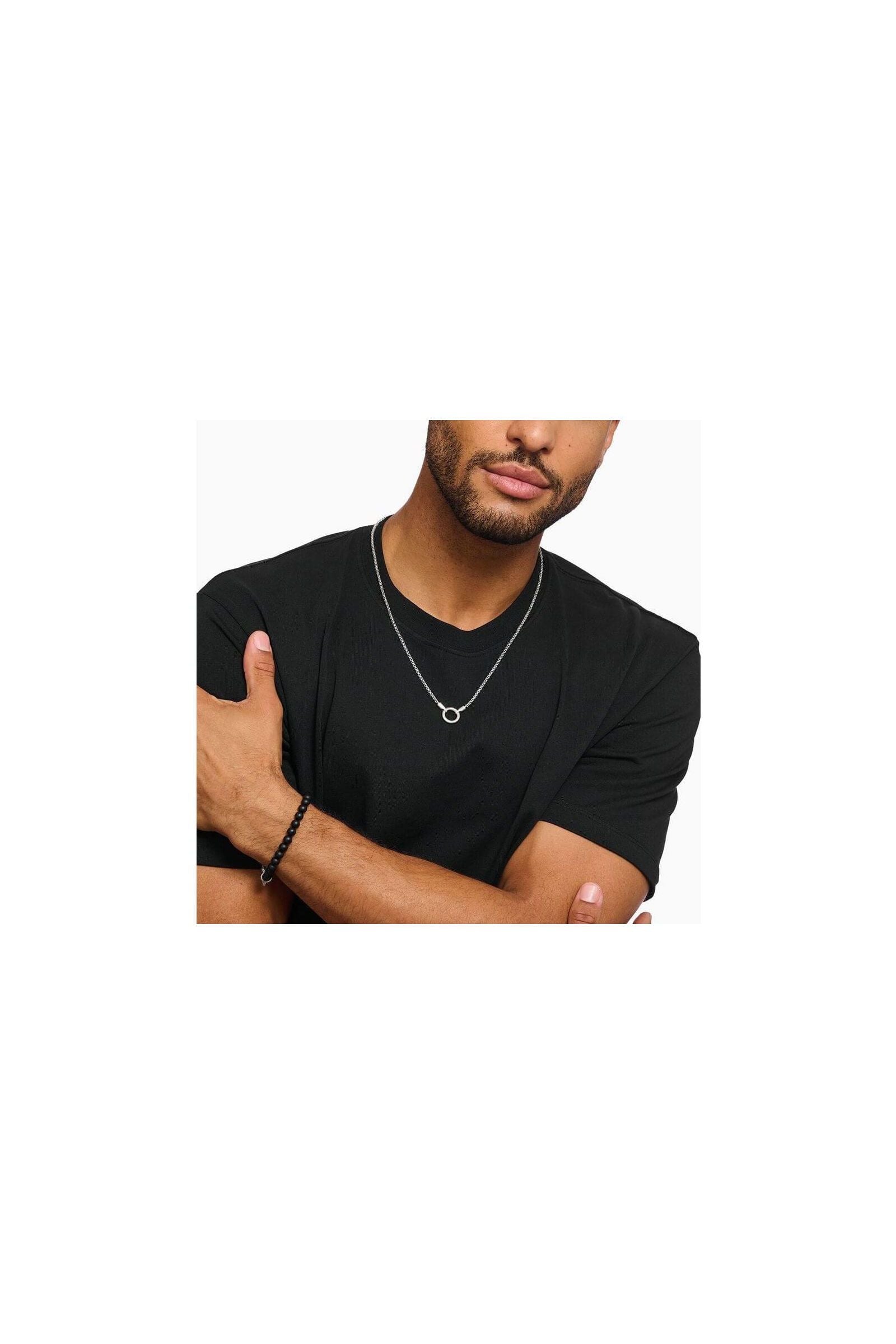 Homme portant un collier vénitien en argent avec fermoir rond, style minimaliste sur t-shirt noir.
