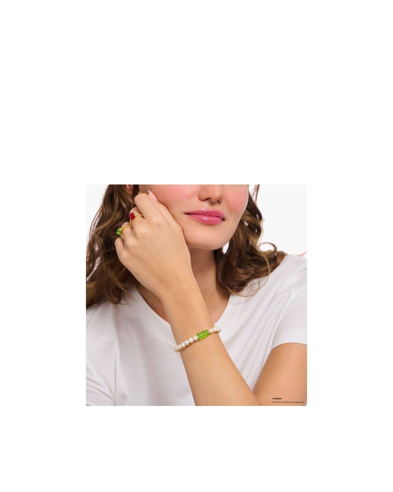 Bracelet de perles d'eau douce avec ours d'or vert sur le poignet d'une femme, style unique et original.