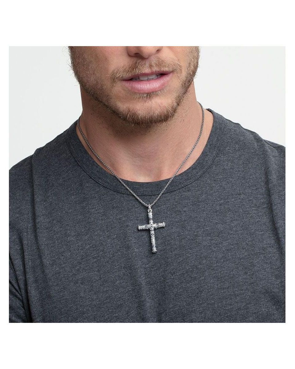 Homme portant un pendentif croix maori en argent, affichant élégance et tradition avec un design unique.