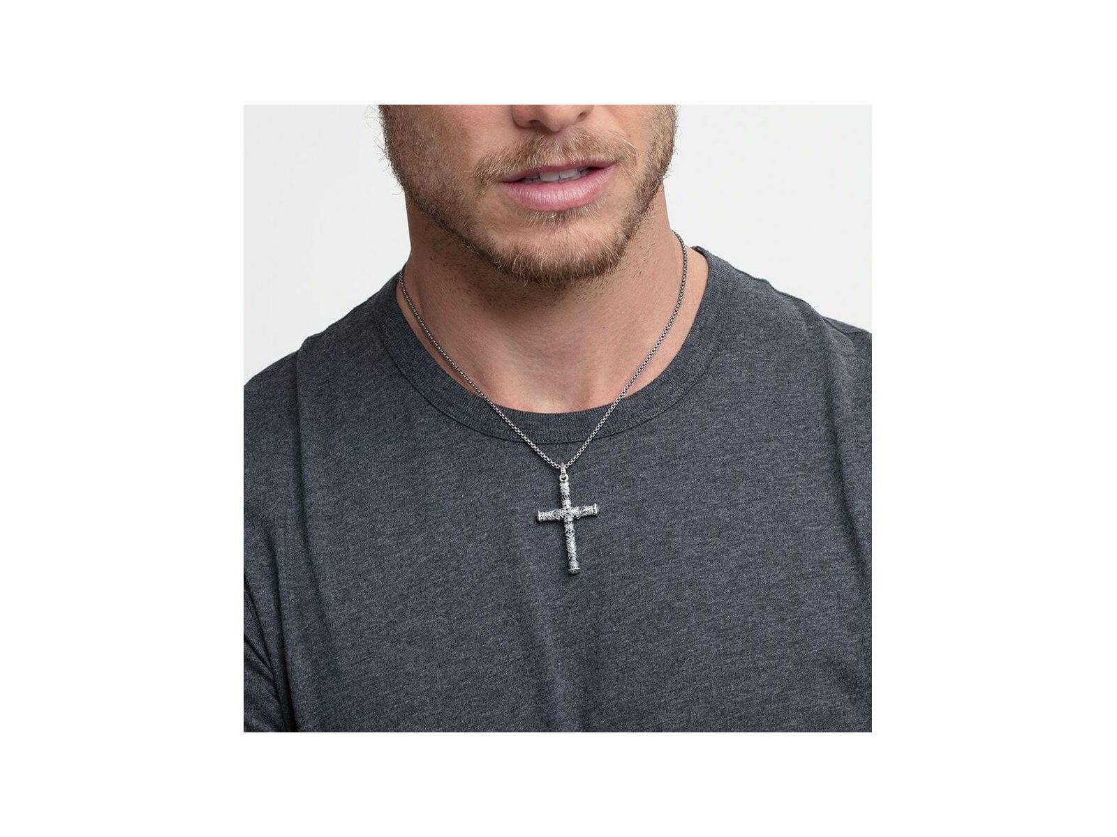 Homme portant un pendentif croix maori en argent, affichant élégance et tradition avec un design unique.