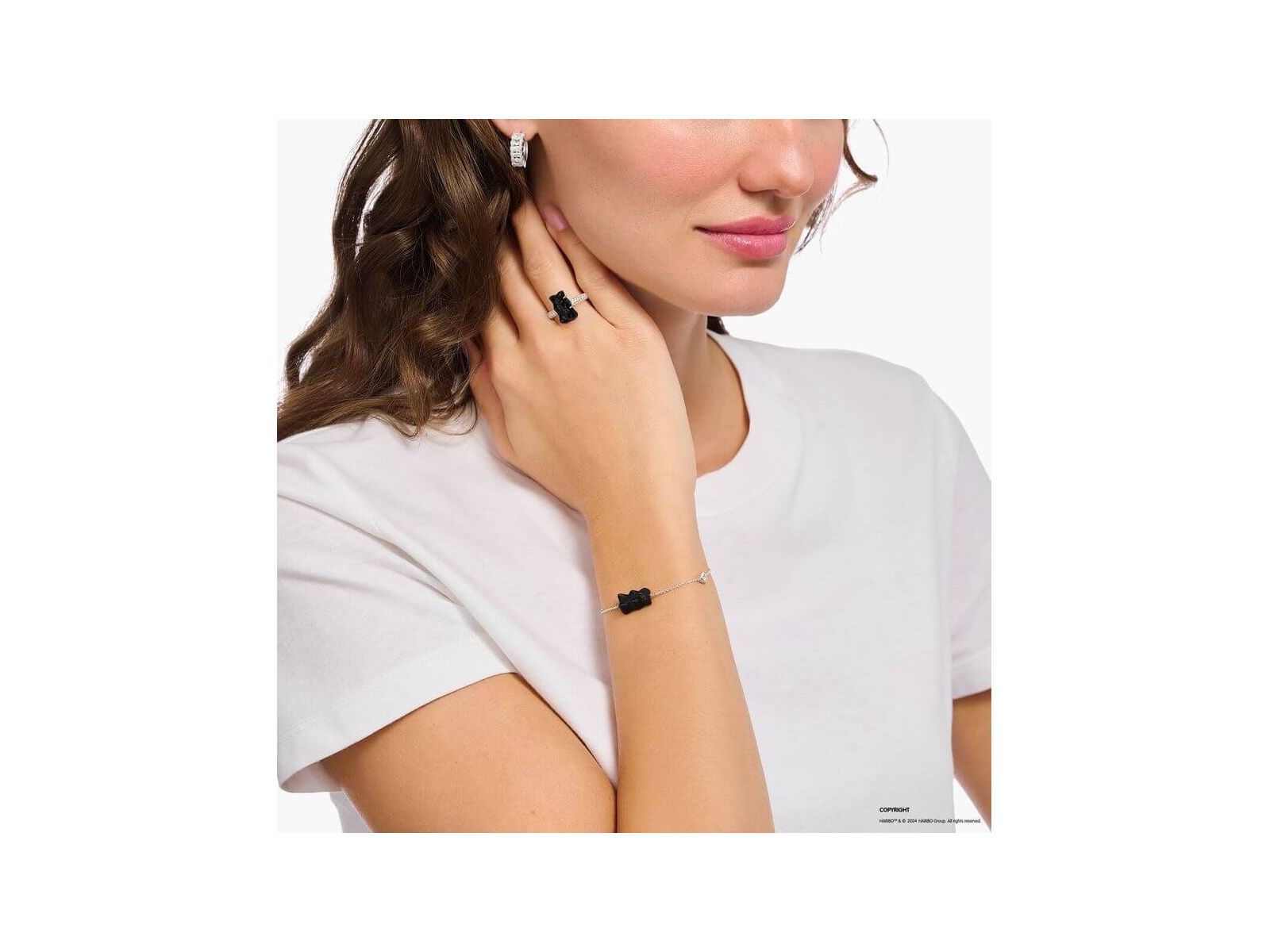 Woman wearing a stylish adjustable bracelet with a black satin crystal bear pendant and freshwater pearl.