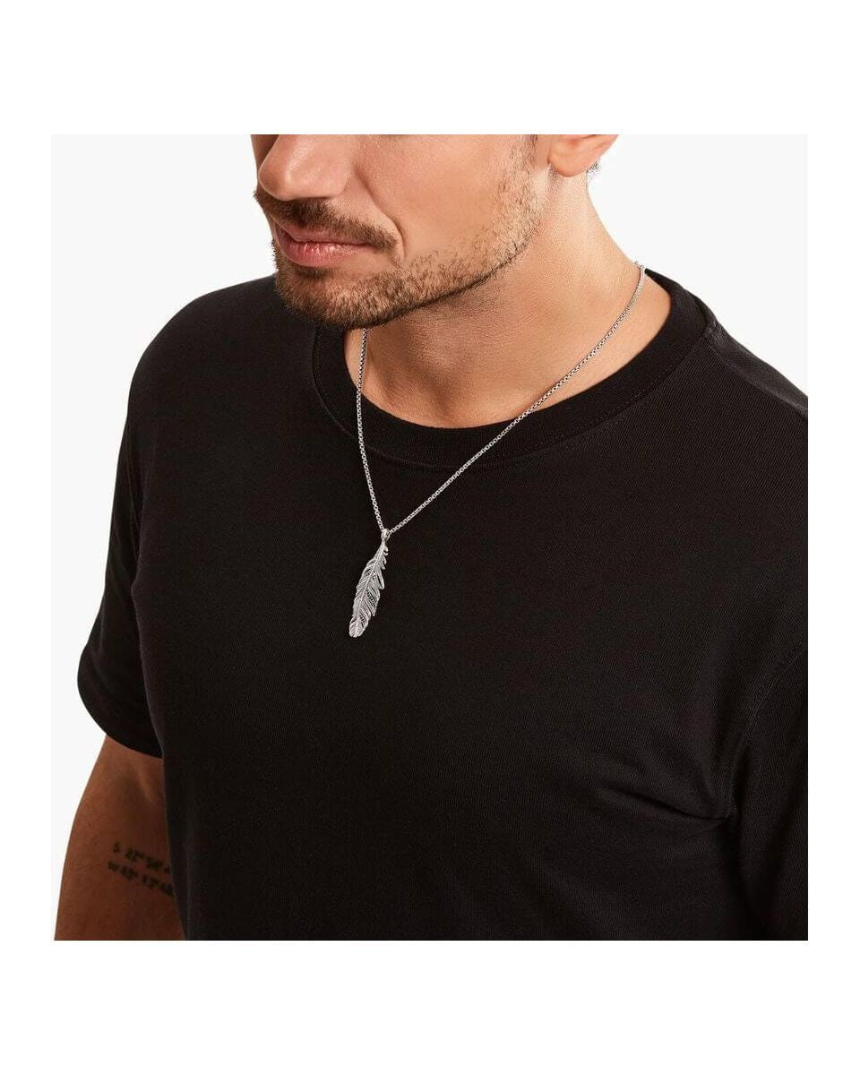 Homme portant un pendentif plume en argent sterling noirci, ajoutant une touche d'élégance à son look décontracté.