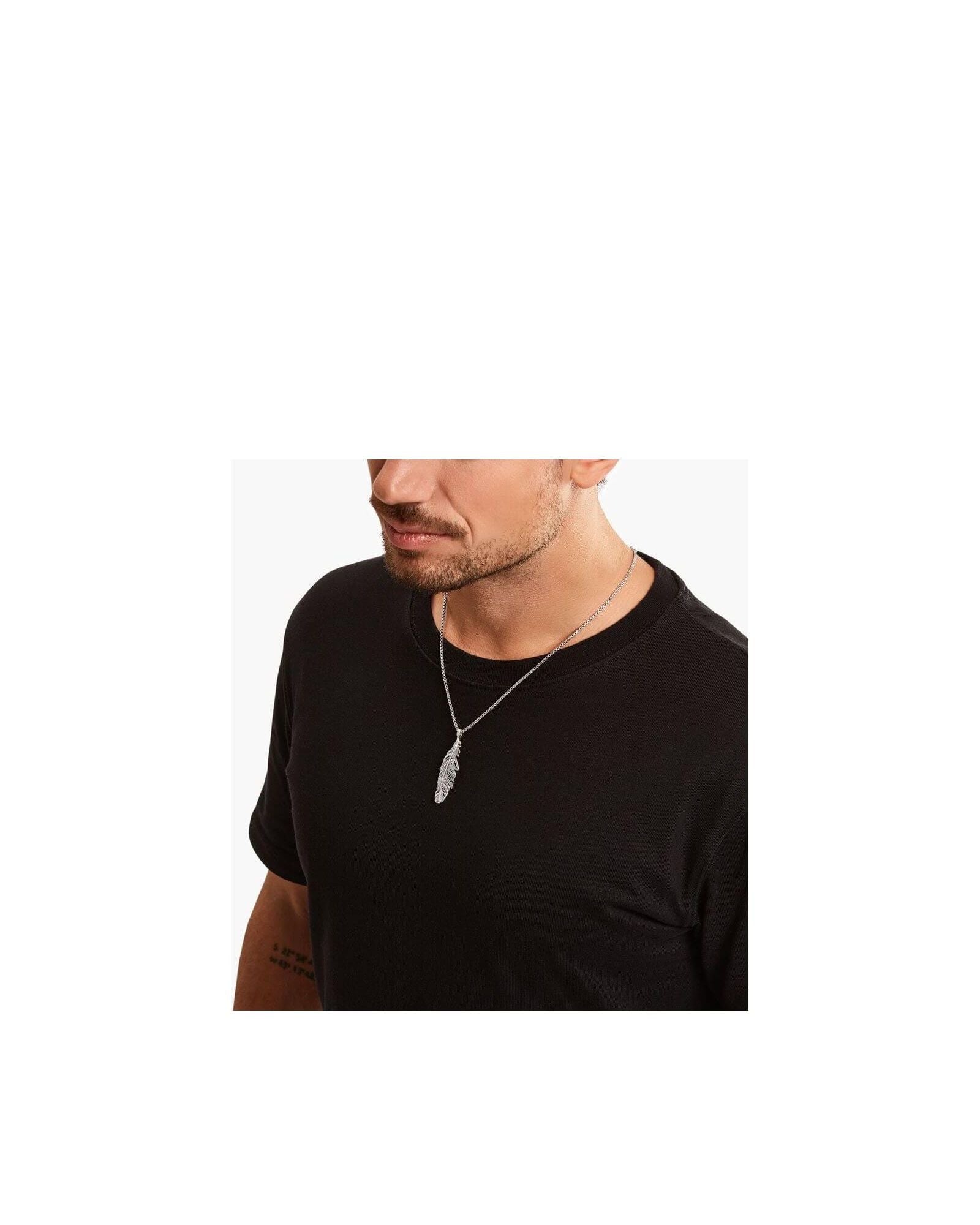 Homme portant un pendentif plume en argent sterling noirci, ajoutant une touche d'élégance à son look décontracté.