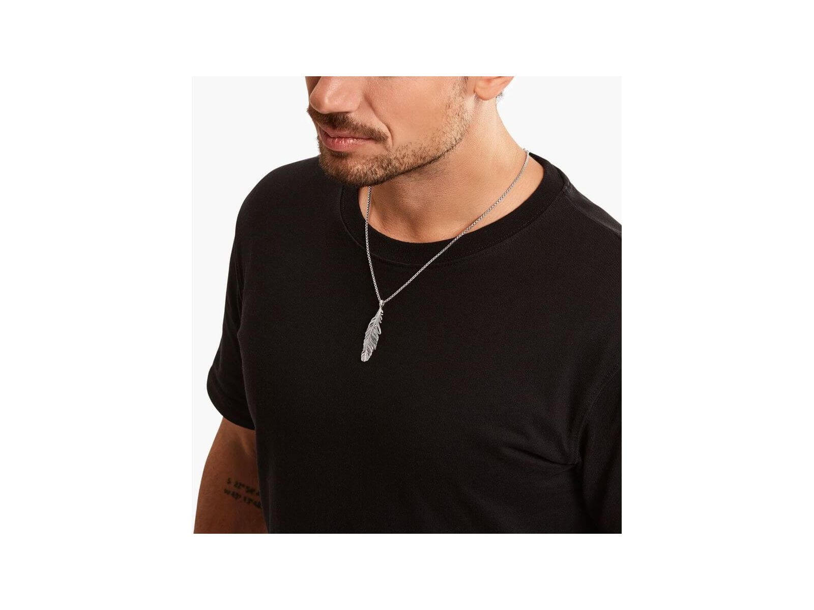 Homme portant un pendentif plume en argent sterling noirci, ajoutant une touche d'élégance à son look décontracté.