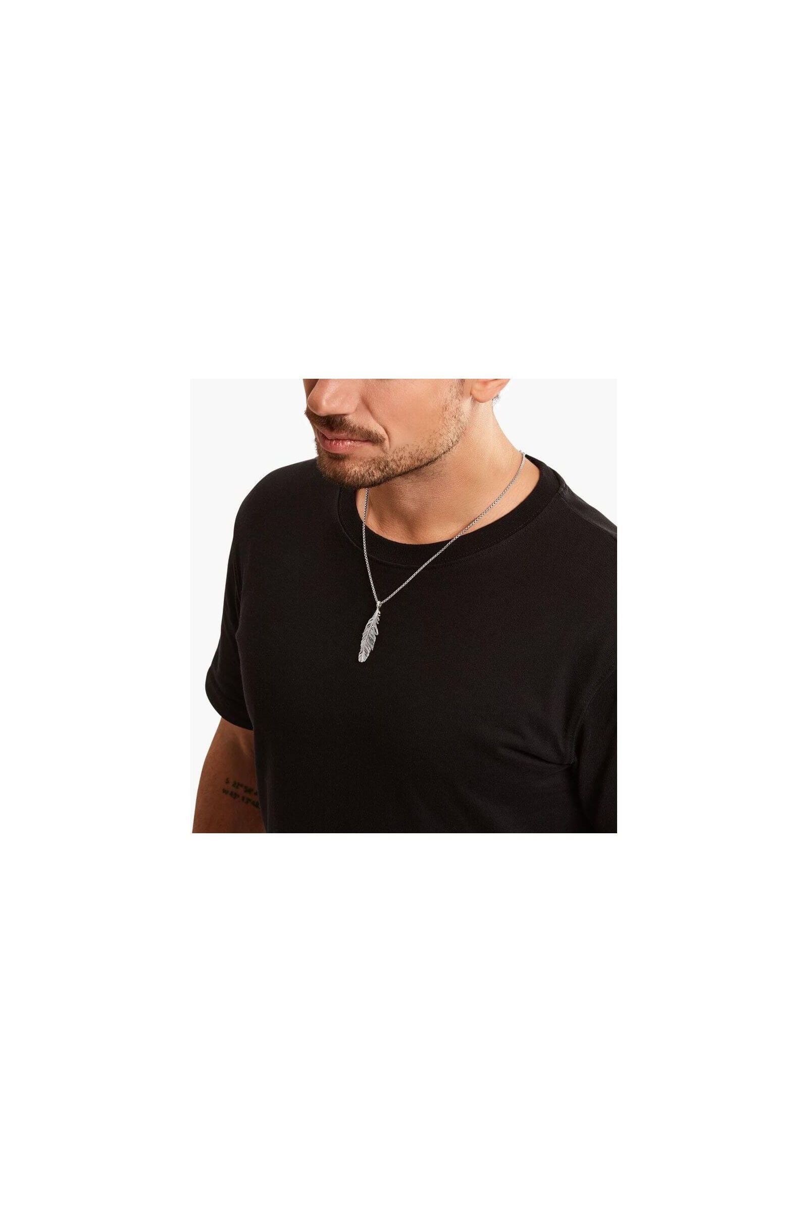 Homme portant un pendentif plume en argent sterling noirci, ajoutant une touche d'élégance à son look décontracté.