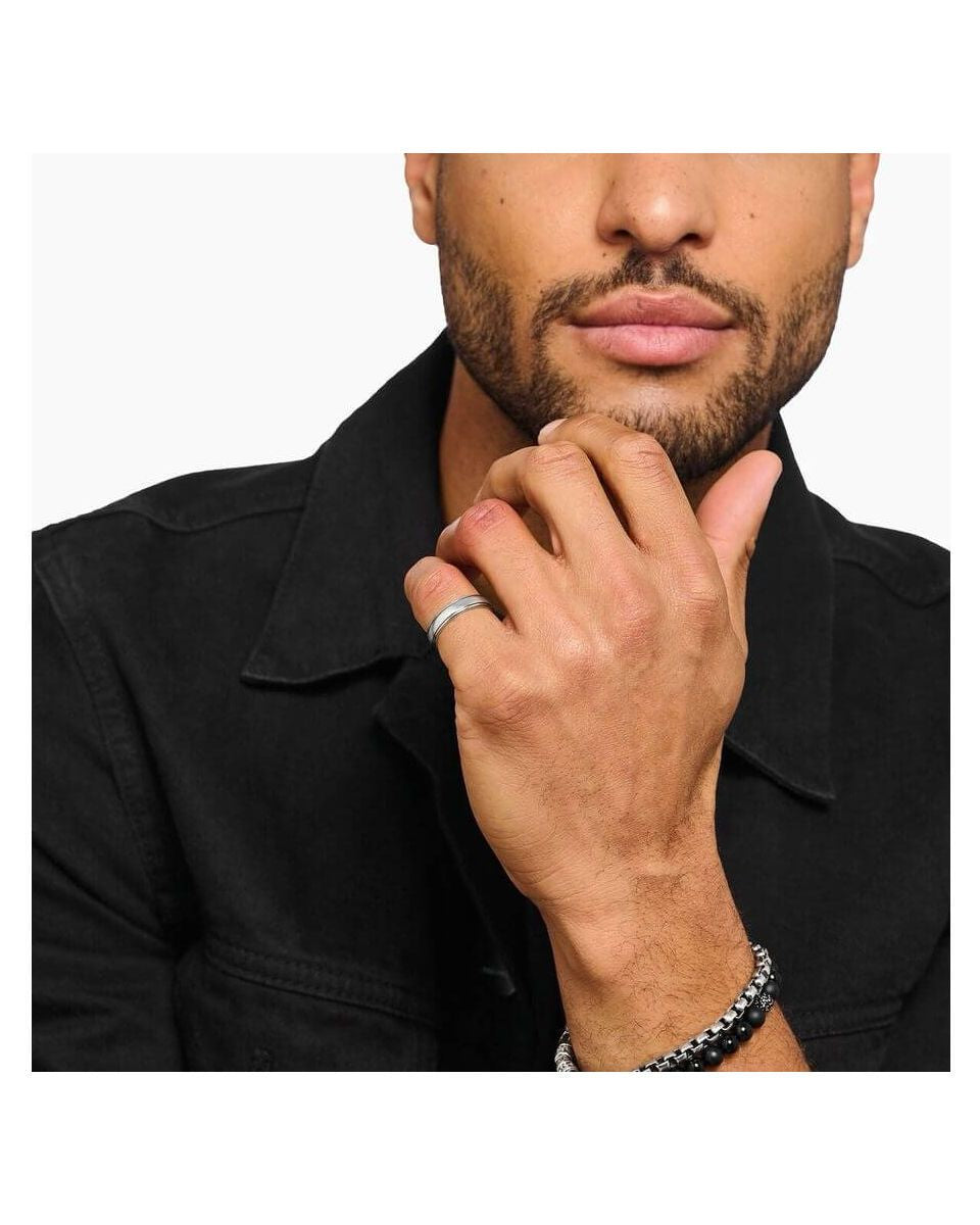 Man wearing a sleek silver band ring and bracelets, showcasing minimalist jewelry style.
