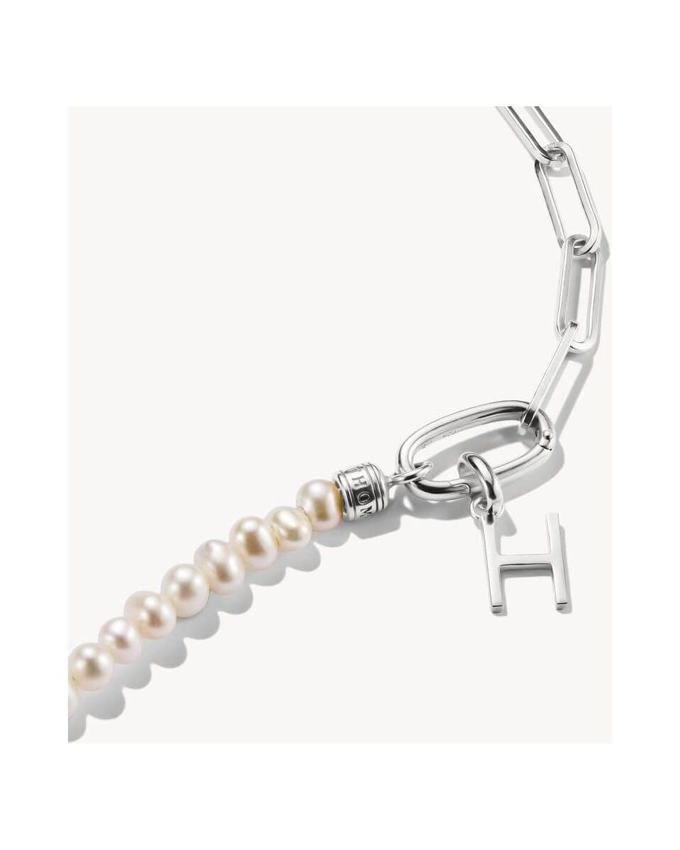 Close-up of a silver charm pendant with a letter 'H' and pearls, perfect for personalized jewelry.