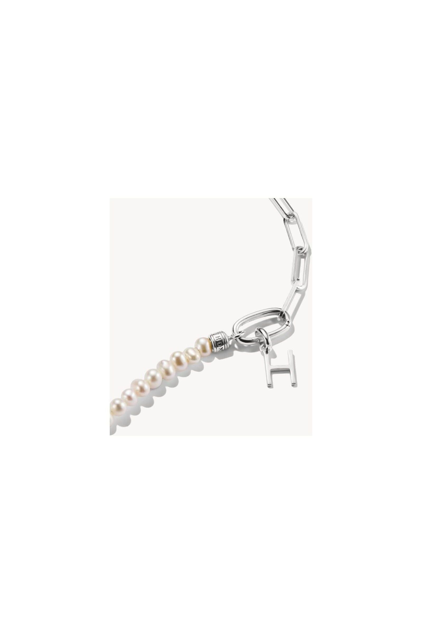 Close-up of a silver charm pendant with a letter 'H' and pearls, perfect for personalized jewelry.