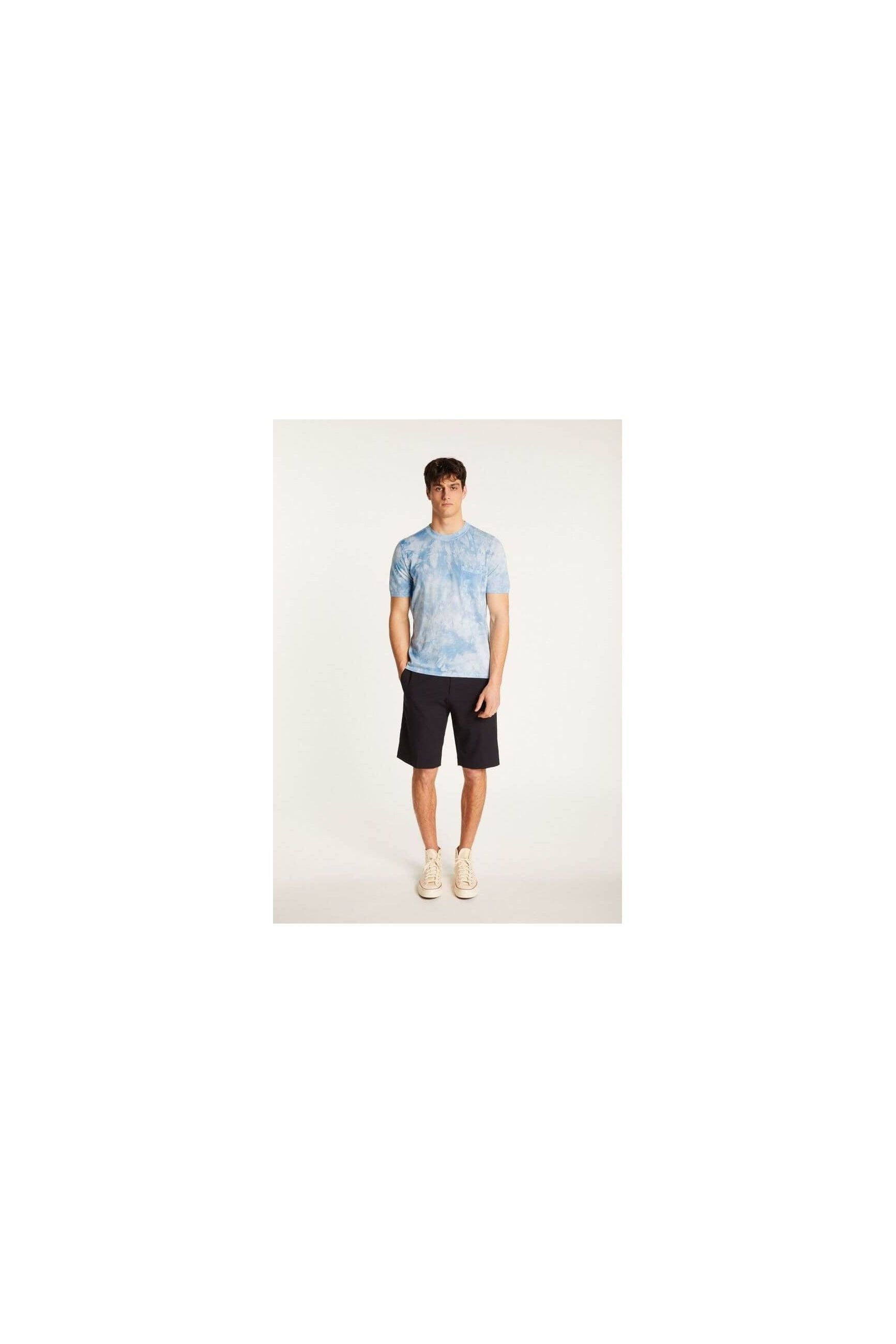 Model wearing a light blue tie-dye T-shirt paired with dark shorts and sneakers.