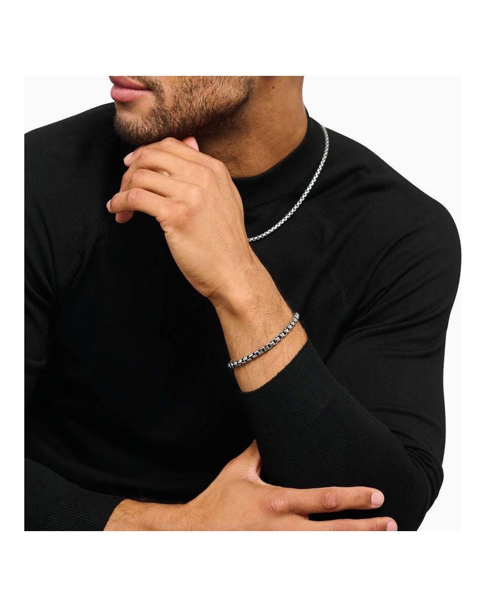 Homme portant un bracelet en argent box chain, avec un design élégant, associé à un t-shirt noir.