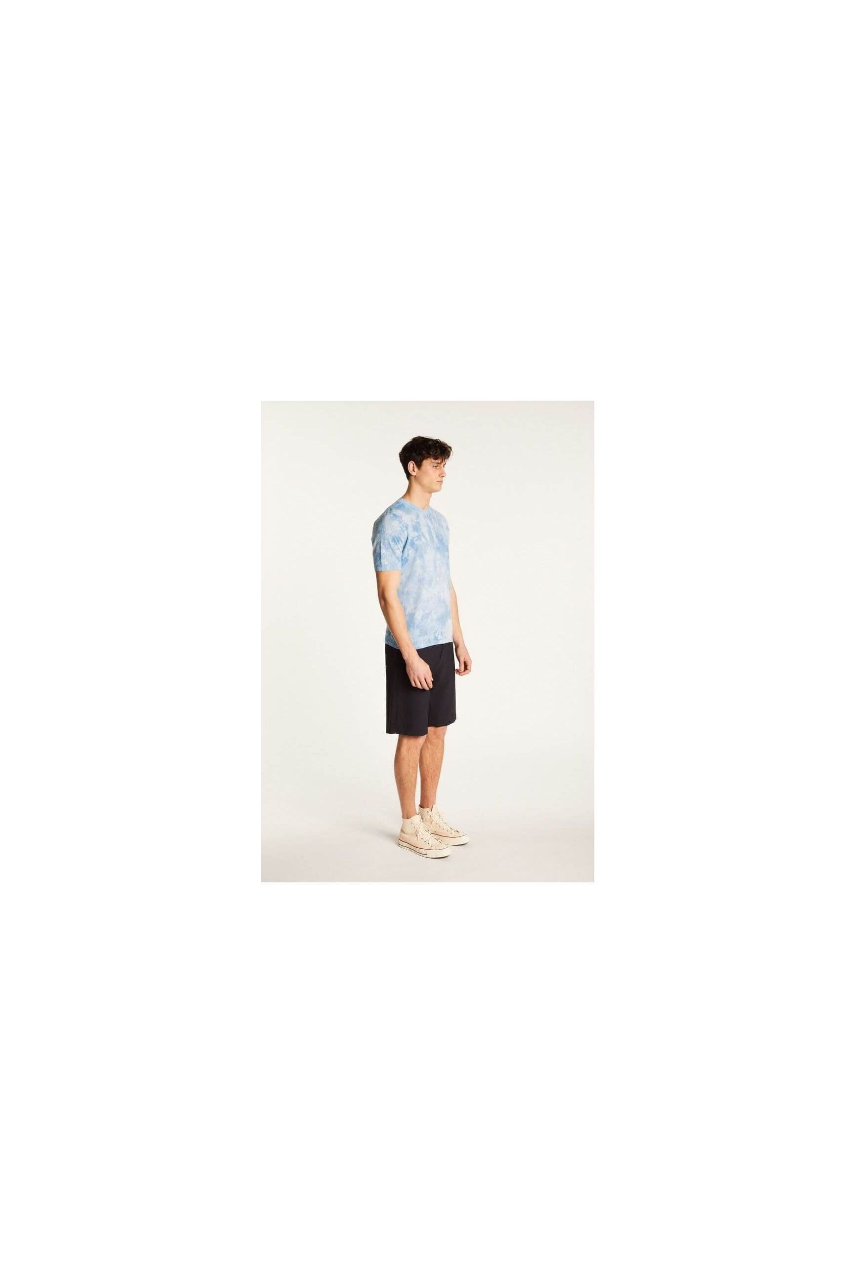 Young man wearing a blue tie-dye T-Shirt and black shorts, showcasing casual summer style.