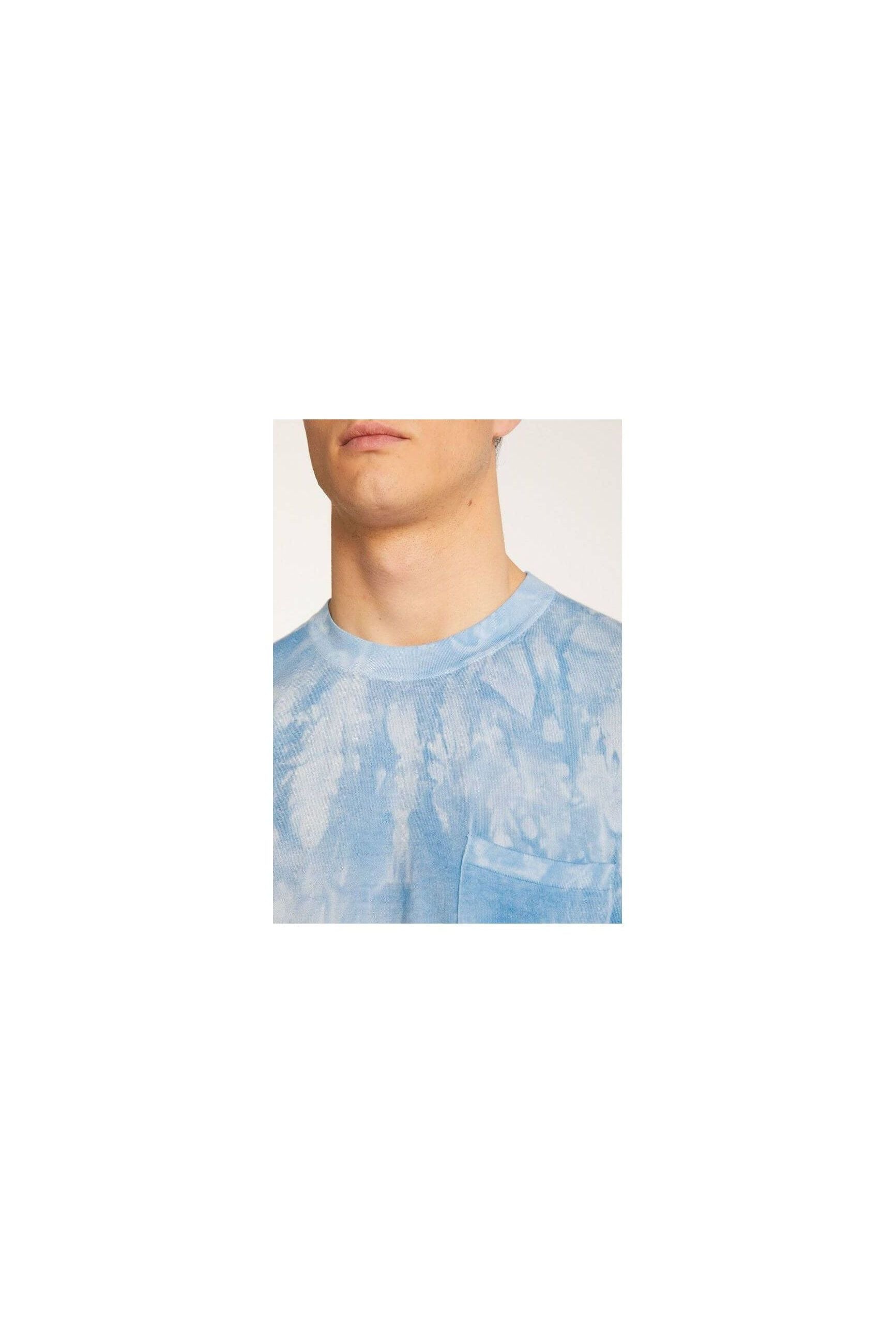 Close-up of a man wearing a light blue tie-dye t-shirt with a pocket, highlighting its modern design and comfort.