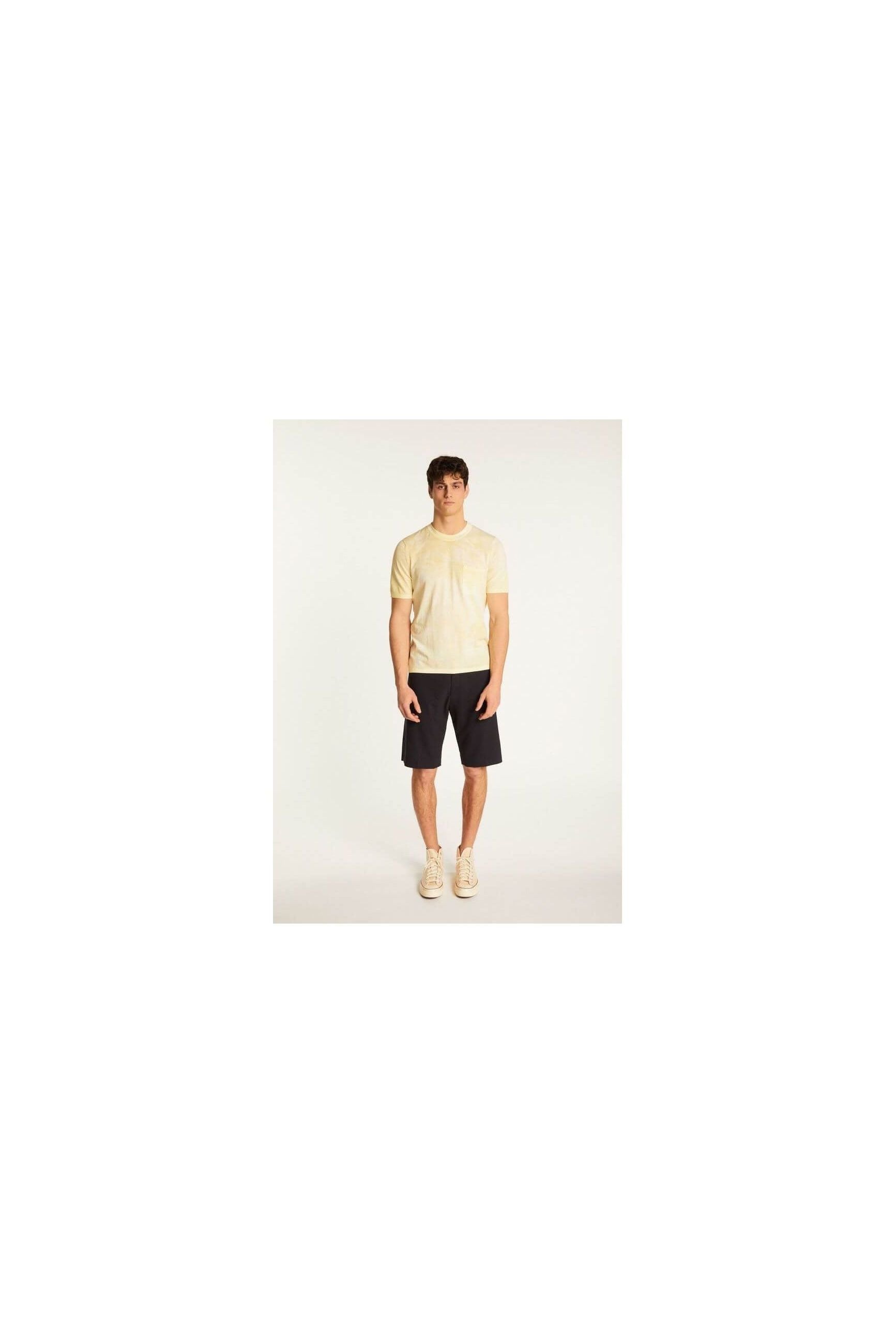 Model wearing the T-Shirt Marquez in light yellow, paired with dark shorts, showcasing a casual summer look.