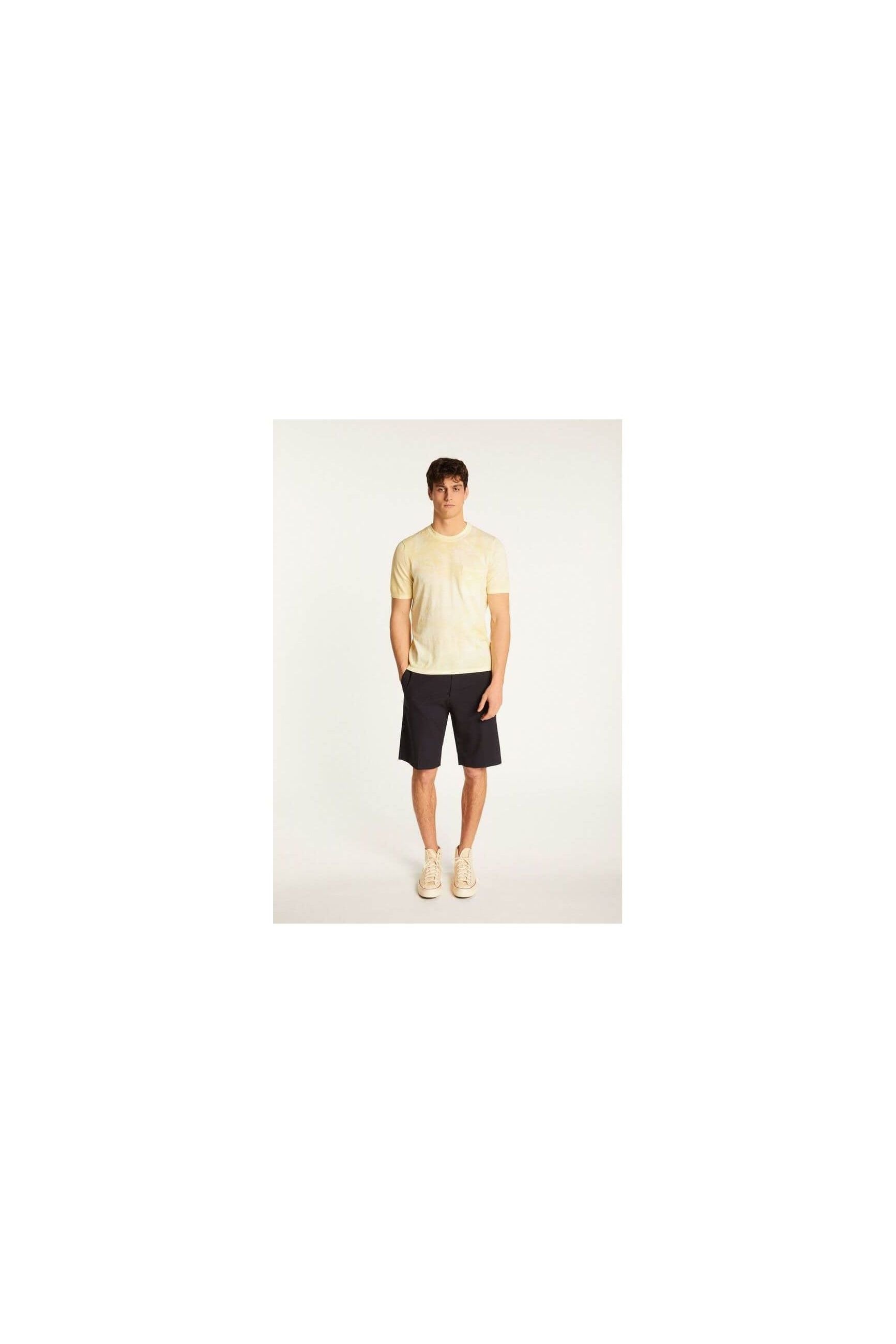Homme portant un t-shirt jaune clair et un short noir, mettant en avant un look décontracté et élégant.