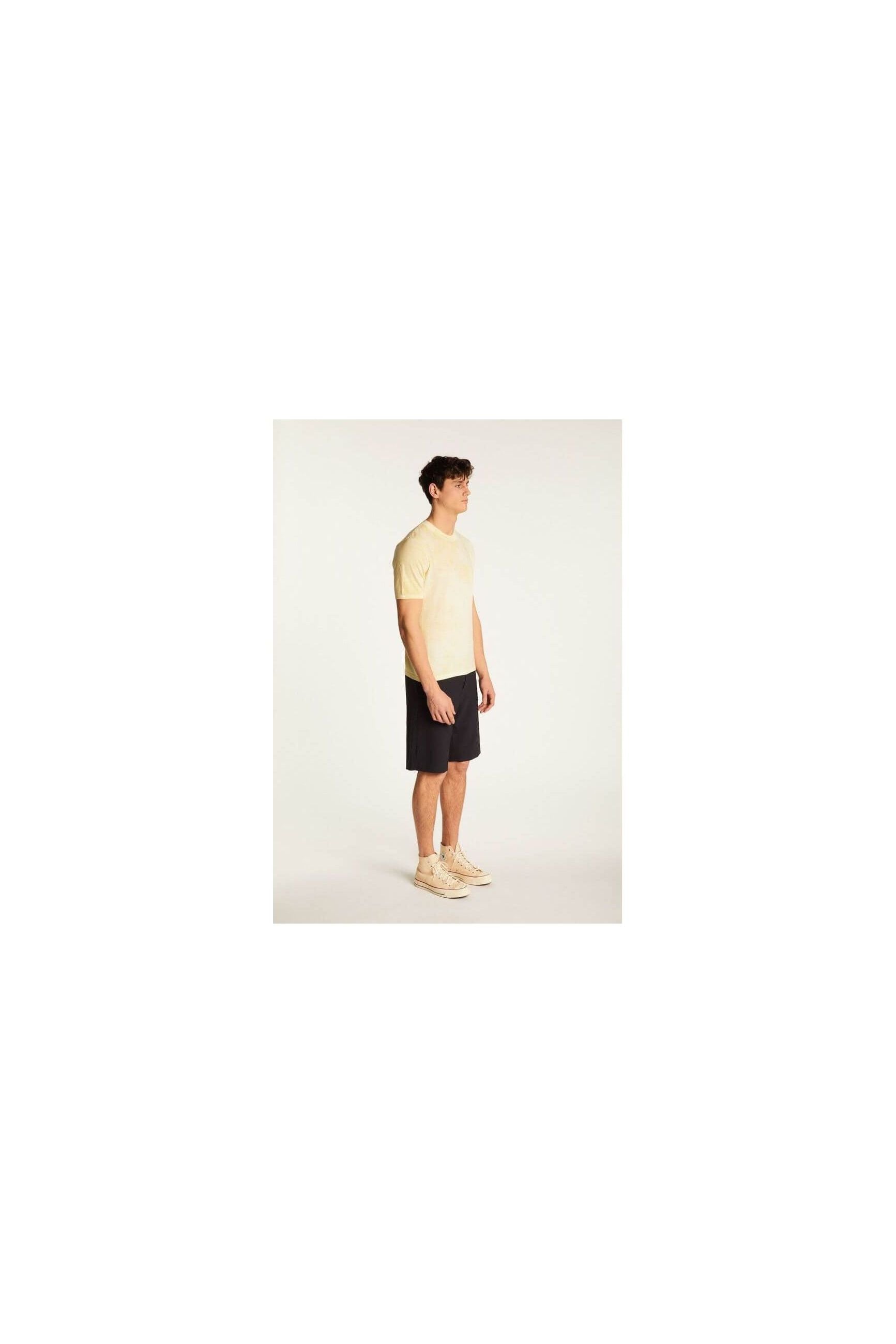 Model wearing a light yellow T-Shirt Marquez paired with dark shorts and sneakers.