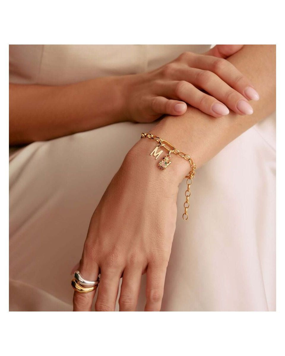 Bracelet charm en or avec lettres, design élégant et personnalisable, porté sur un poignet féminin.