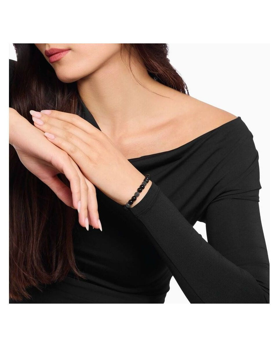 Femme portant un bracelet en obsidienne et zirconium noir, style rock-chic, élégant avec des beads polies et mate.