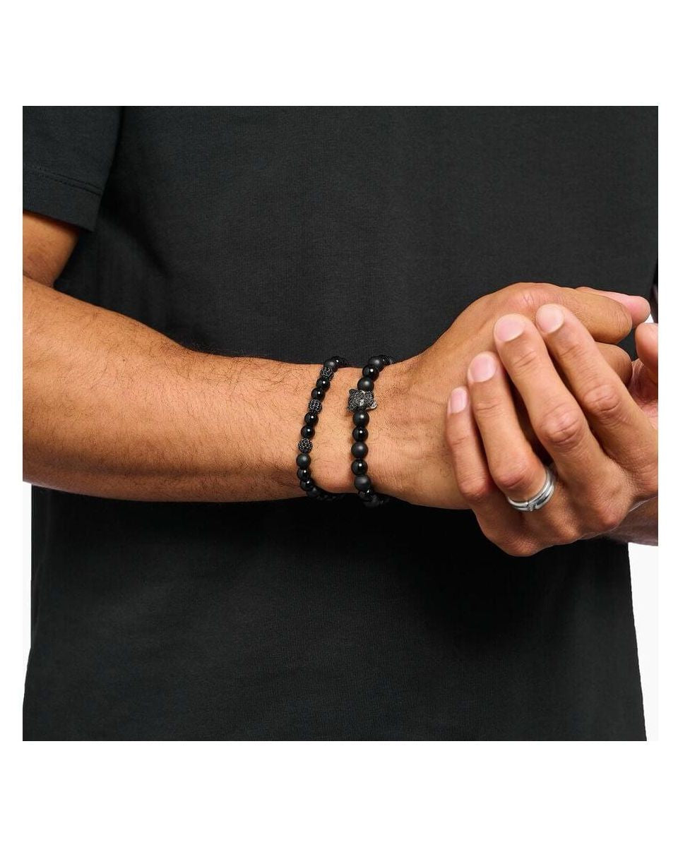 Homme portant un bracelet en obsidienne et zirconium noir, style rock-chic à la mode.