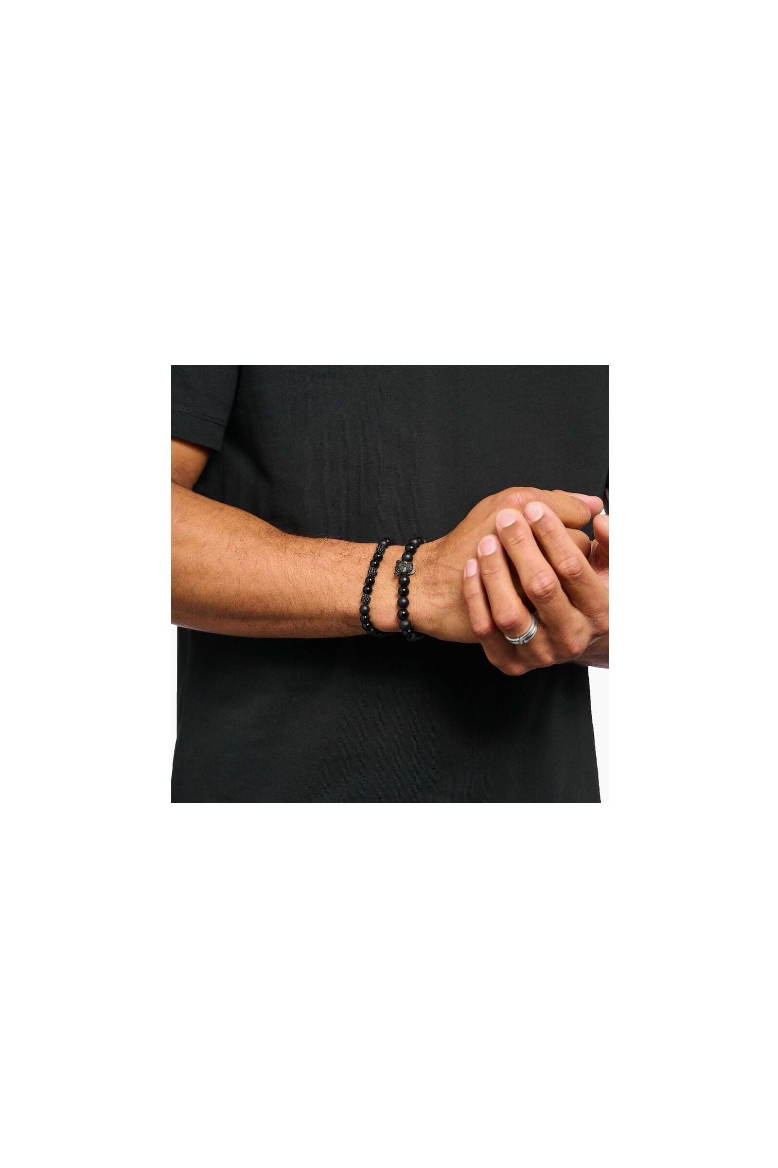 Homme portant un bracelet en obsidienne et zirconium noir, style rock-chic à la mode.