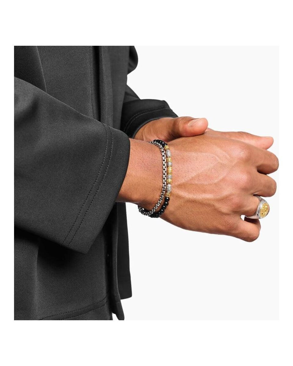 Homme portant un bracelet en argent et des accessoires de mode élégants sur une chemise noire.