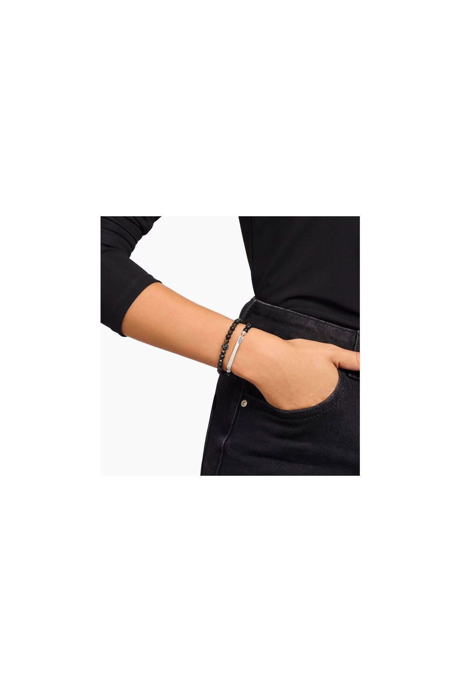 Bracelet à graver avec perles en obsidienne noire et barrette en argent, porté sur le poignet d'une personne.