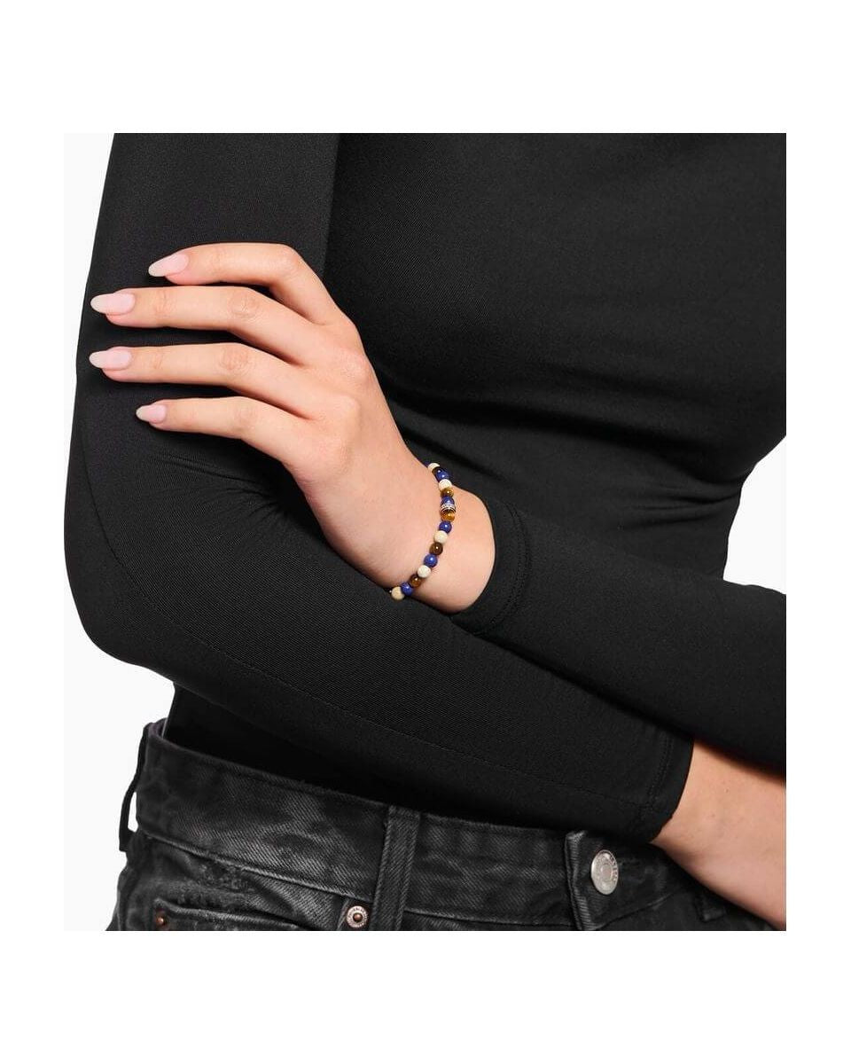 Bracelet en beads bruns et bleus sur un poignet, conçu avec jaspe et œil de tigre, ajoutant une touche d'élégance.