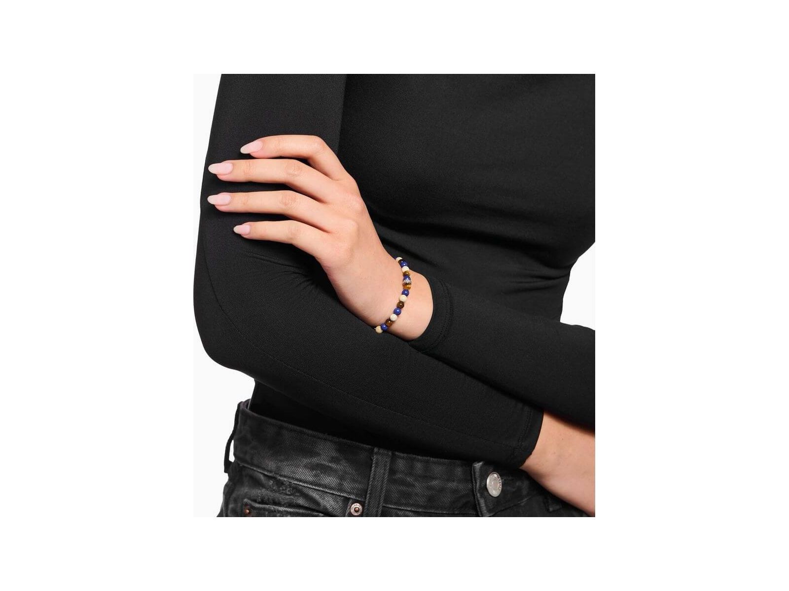 Bracelet en beads bruns et bleus sur un poignet, conçu avec jaspe et œil de tigre, ajoutant une touche d'élégance.