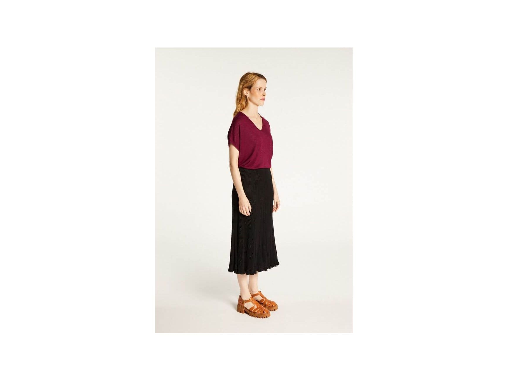 Model showcasing Larra T-shirt, a chic V-neck design in burgundy paired with a flowy black skirt, highlighted for elegance and comfort.