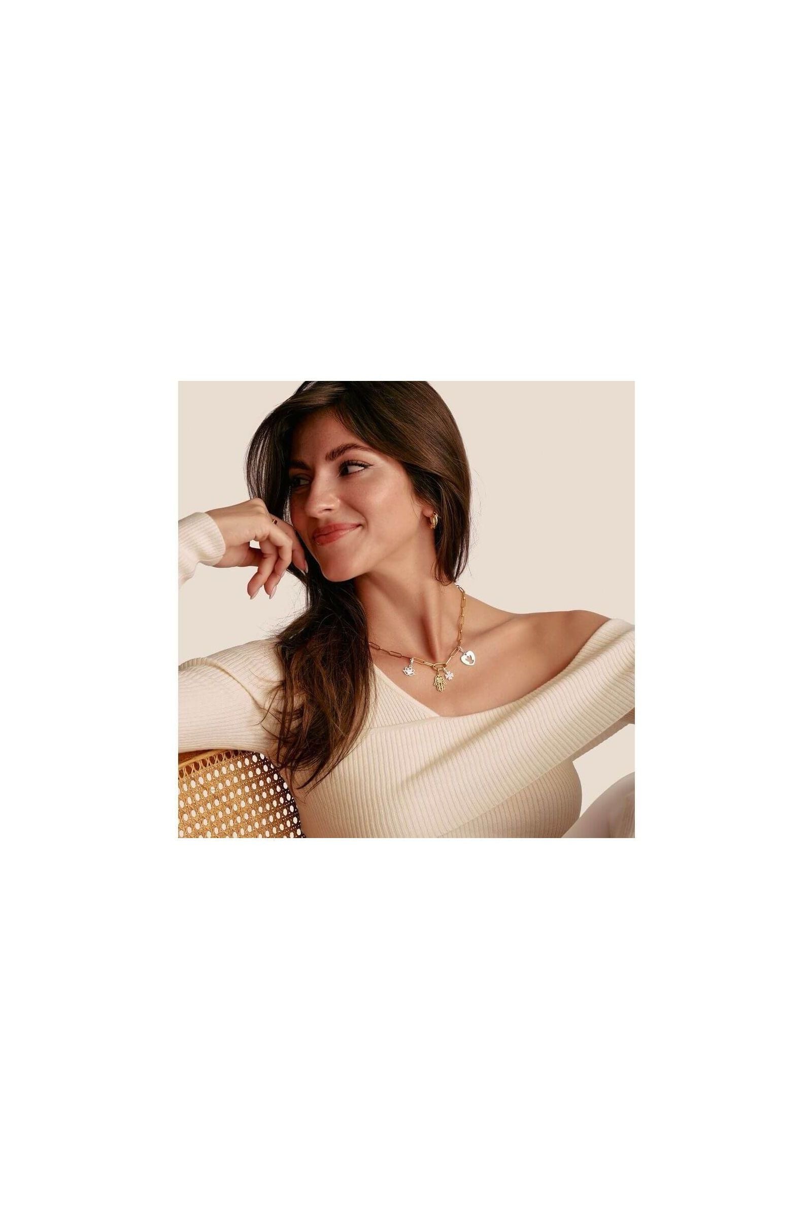 Femme souriante portant un collier élégant avec pendentifs en forme de main Hamsa en or plaqué.