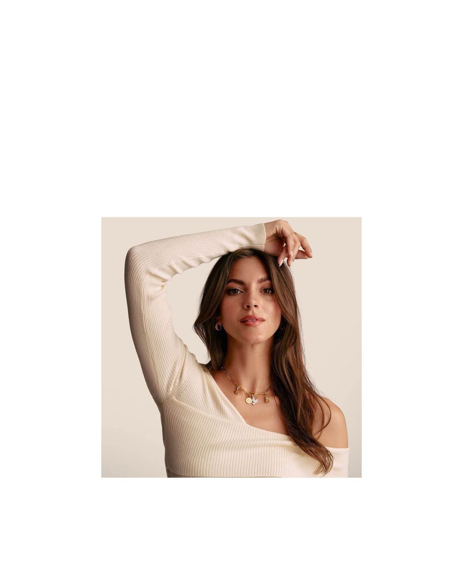Femme portant un pendentif charm en or avec pierres, symbolisant élégance et harmonie.