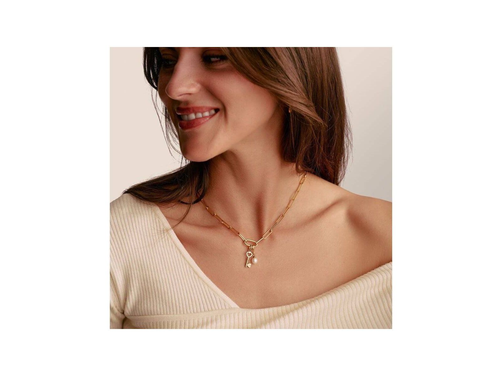 Femme souriante portant le collier Charm Paperclip en or avec Connect Link et breloques, élégant et raffiné.