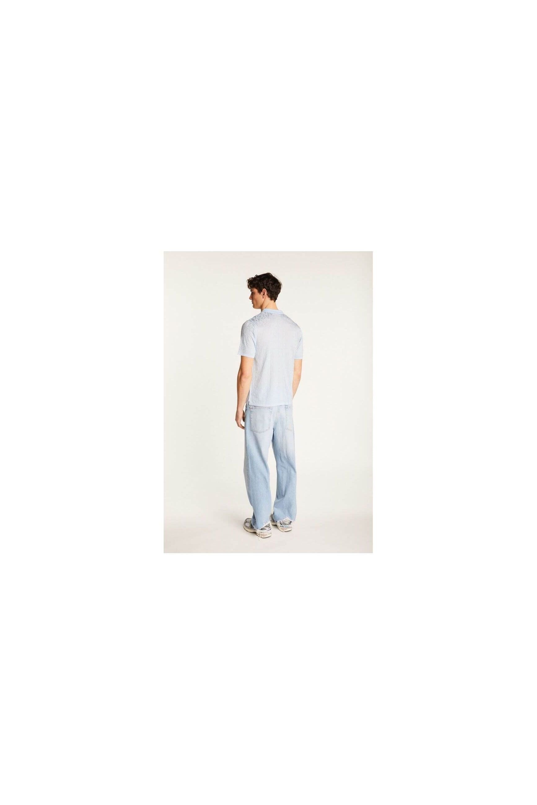 Homme portant une chemise légère et moderne avec un pantalon en jeans, vu de dos.