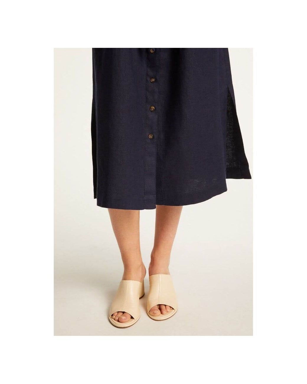 Femme portant la robe Emy en lin léger, avec des sandales claires, mettant en avant l'élégance et le confort.