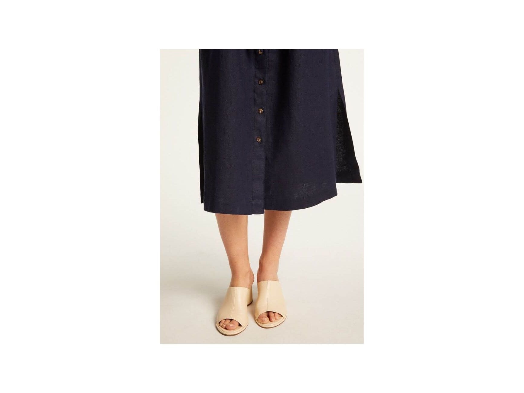 Femme portant la robe Emy en lin léger, avec des sandales claires, mettant en avant l'élégance et le confort.