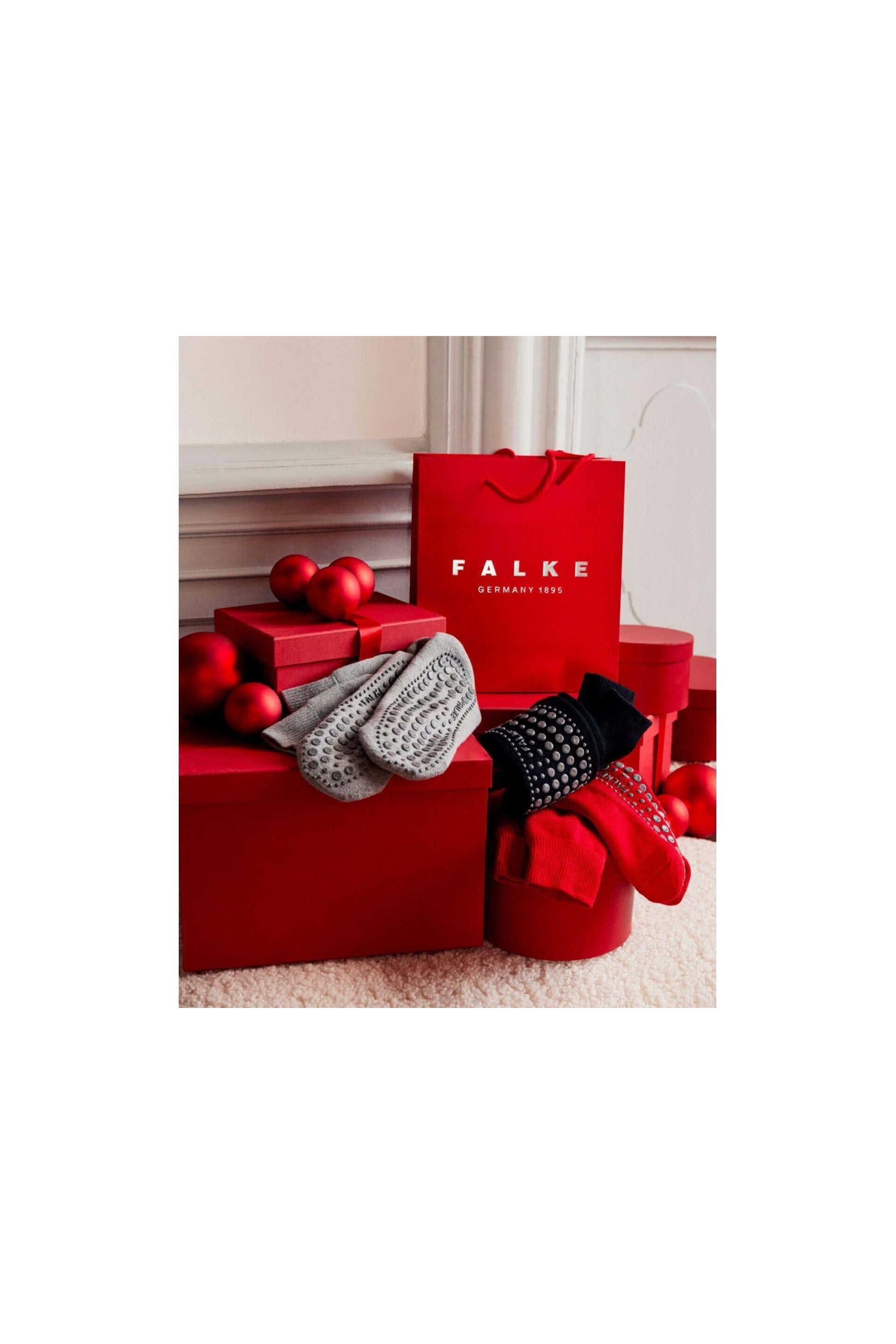 Chaussettes Homepads FALKE en textures grises, noires et rouges, présentées avec des boîtes rouges et boules décoratives.