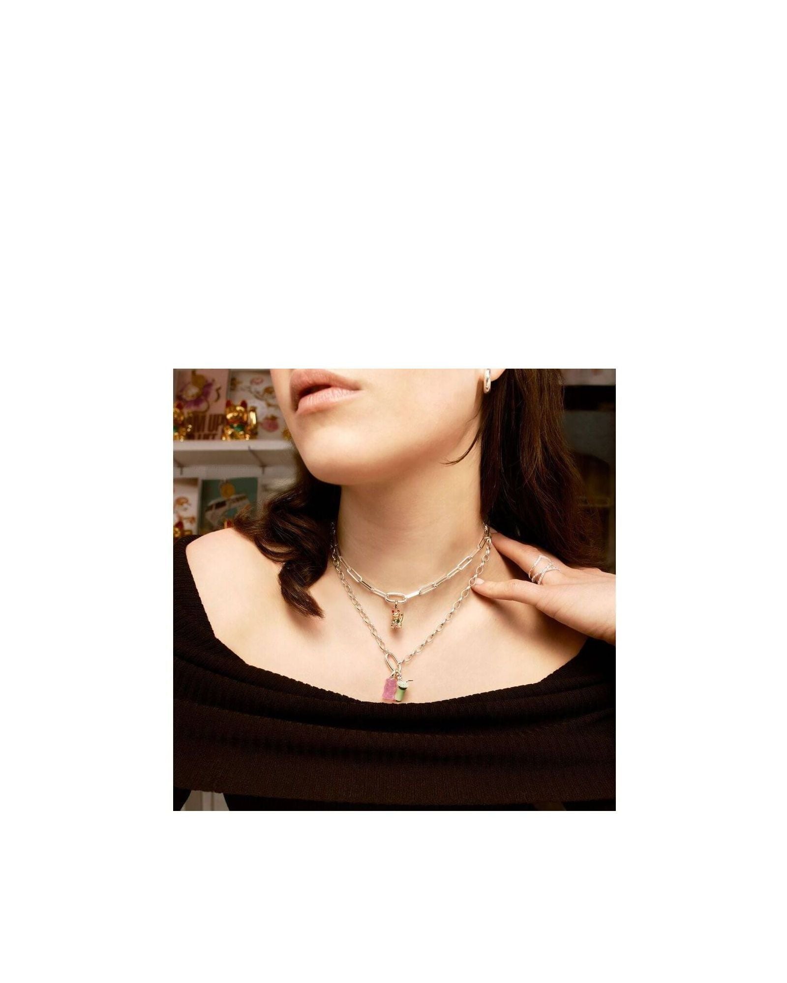 Woman wearing layered silver necklaces with matcha latte charm pendant, showcasing trendy jewelry style.
