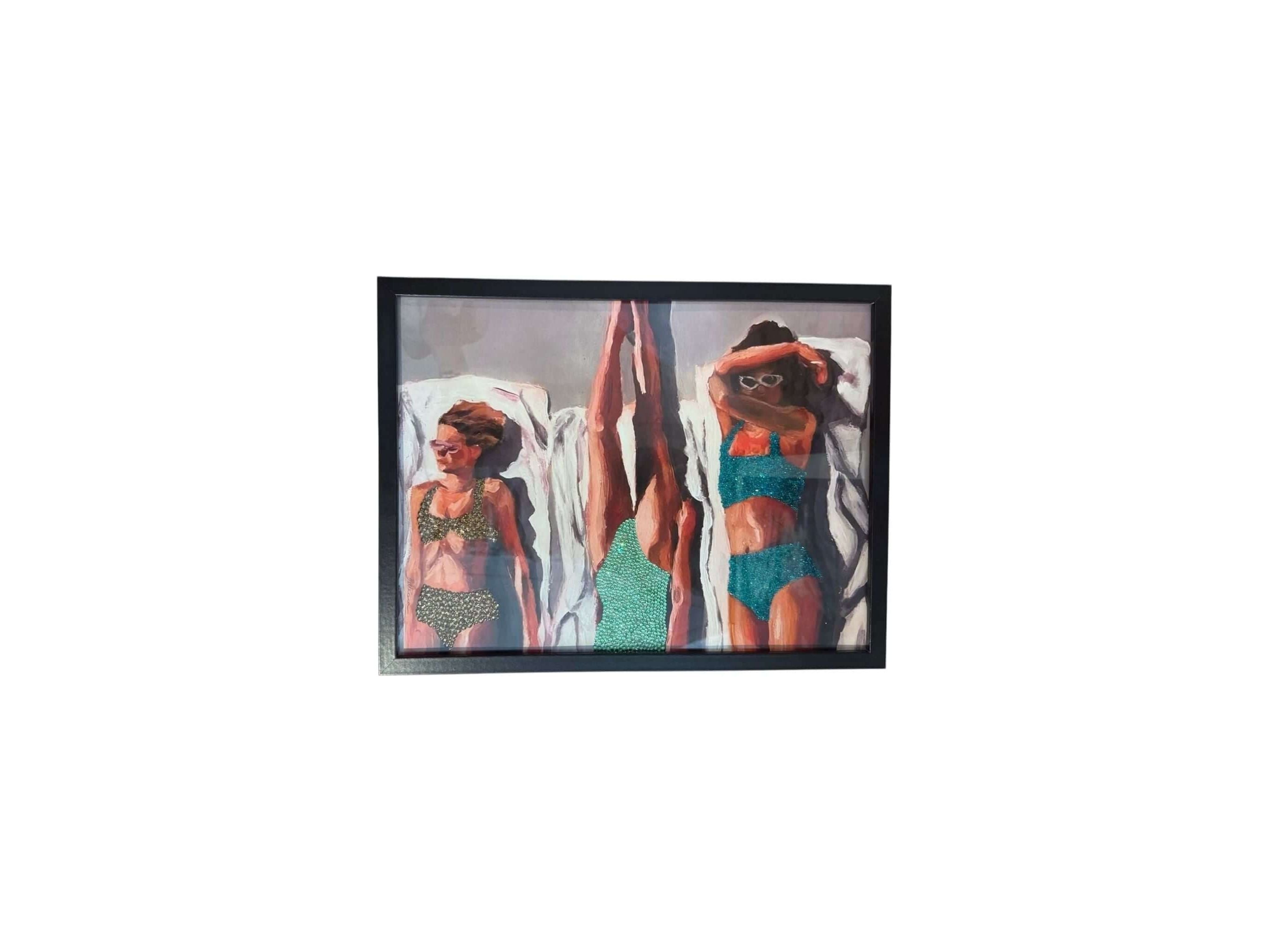 Photo encadrée de trois femmes en maillots de bain bronzant au soleil, ajoutant une touche glamour à votre décoration.