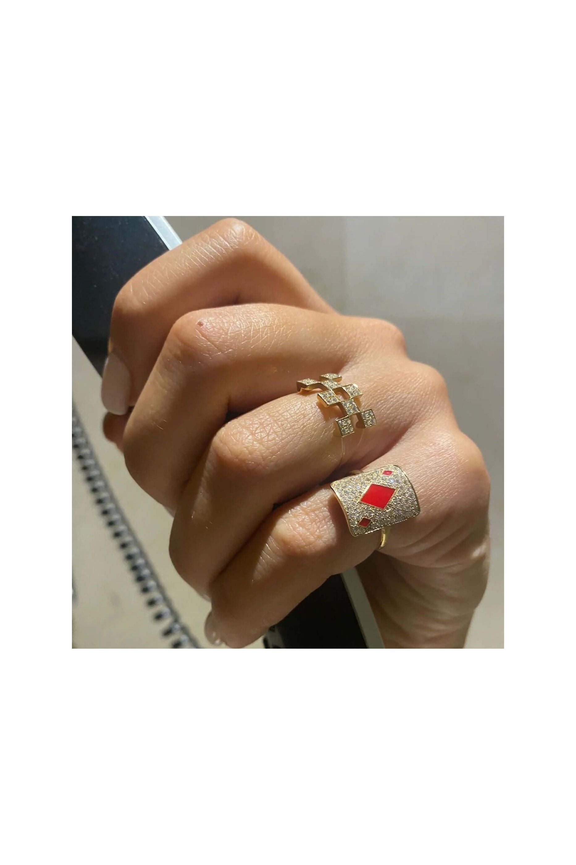 Elegant gold rings adorned with diamonds and red accents, showcasing a stylish hand.