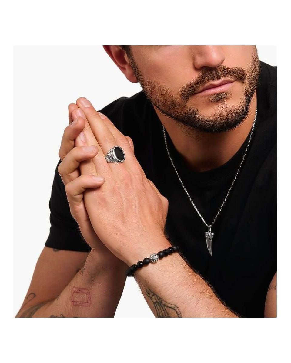 Homme portant une chevalière en argent noirci avec onyx noir, bracelet noir et collier stylé.