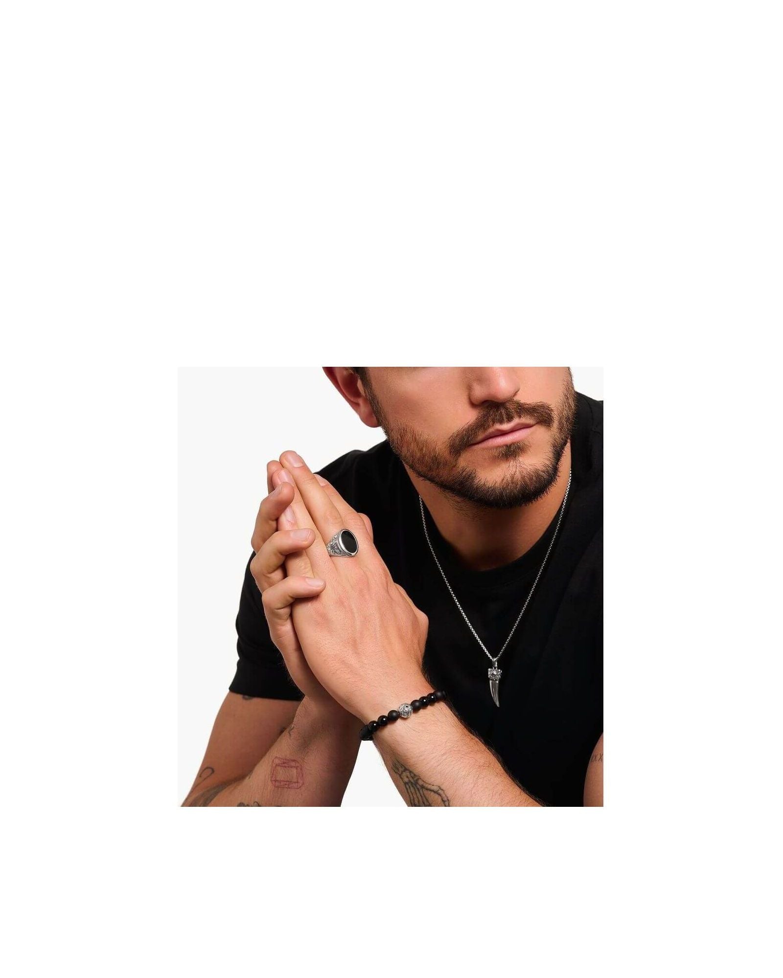 Homme portant une chevalière en argent noirci avec onyx noir, bracelet noir et collier stylé.