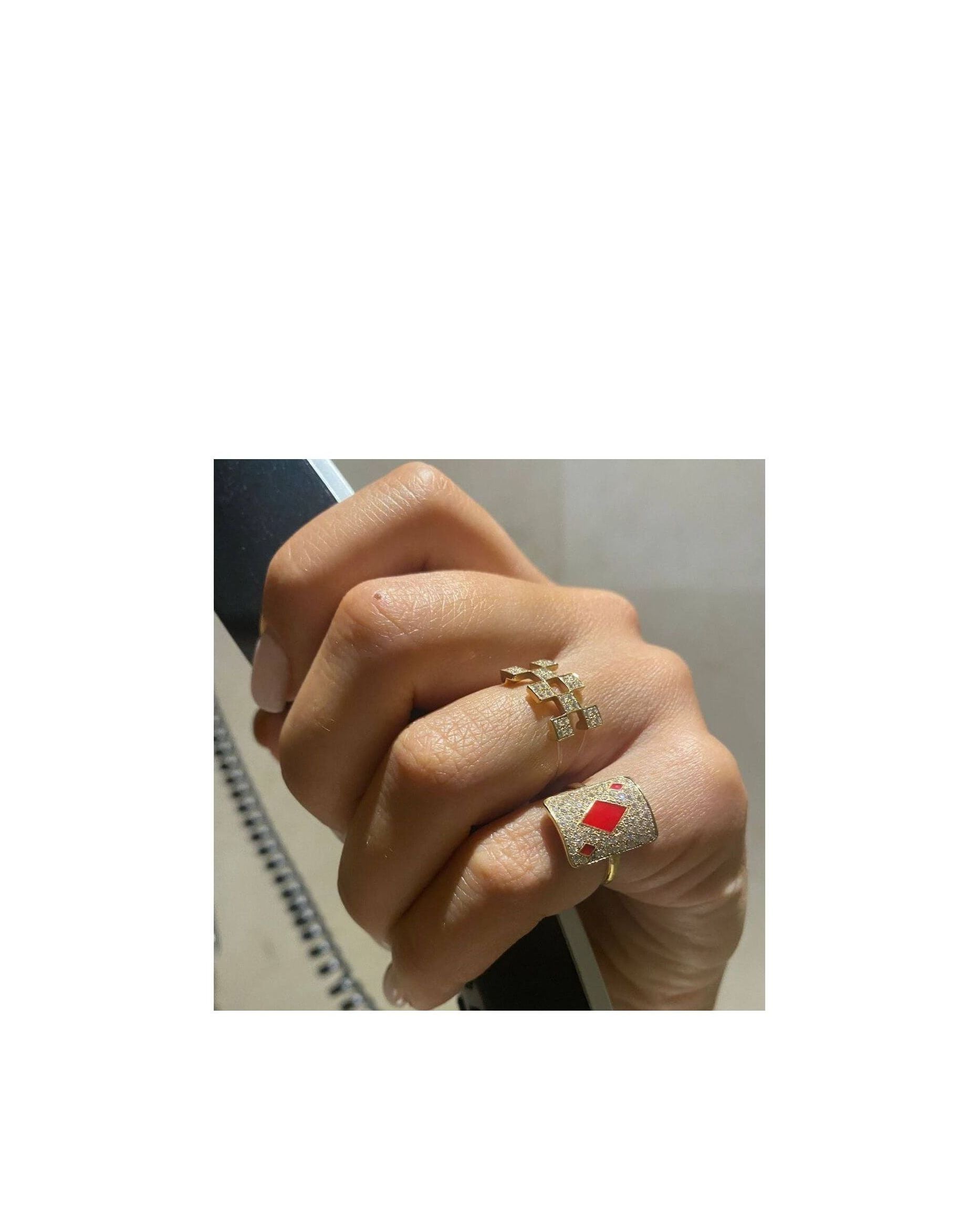 Close-up of a hand wearing two elegant rings, one gold with diamonds and the other with a red gemstone.