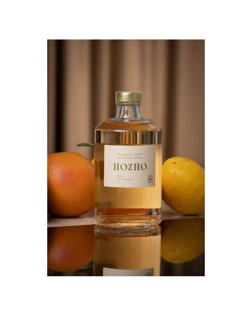 Bouteille de diffuseur HOZHO entourée d'orange et de citron, évoquant une atmosphère revitalisante.