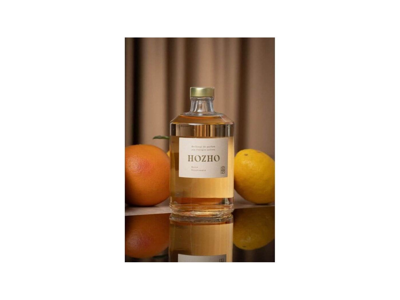 Bouteille de diffuseur HOZHO entourée d'orange et de citron, évoquant une atmosphère revitalisante.