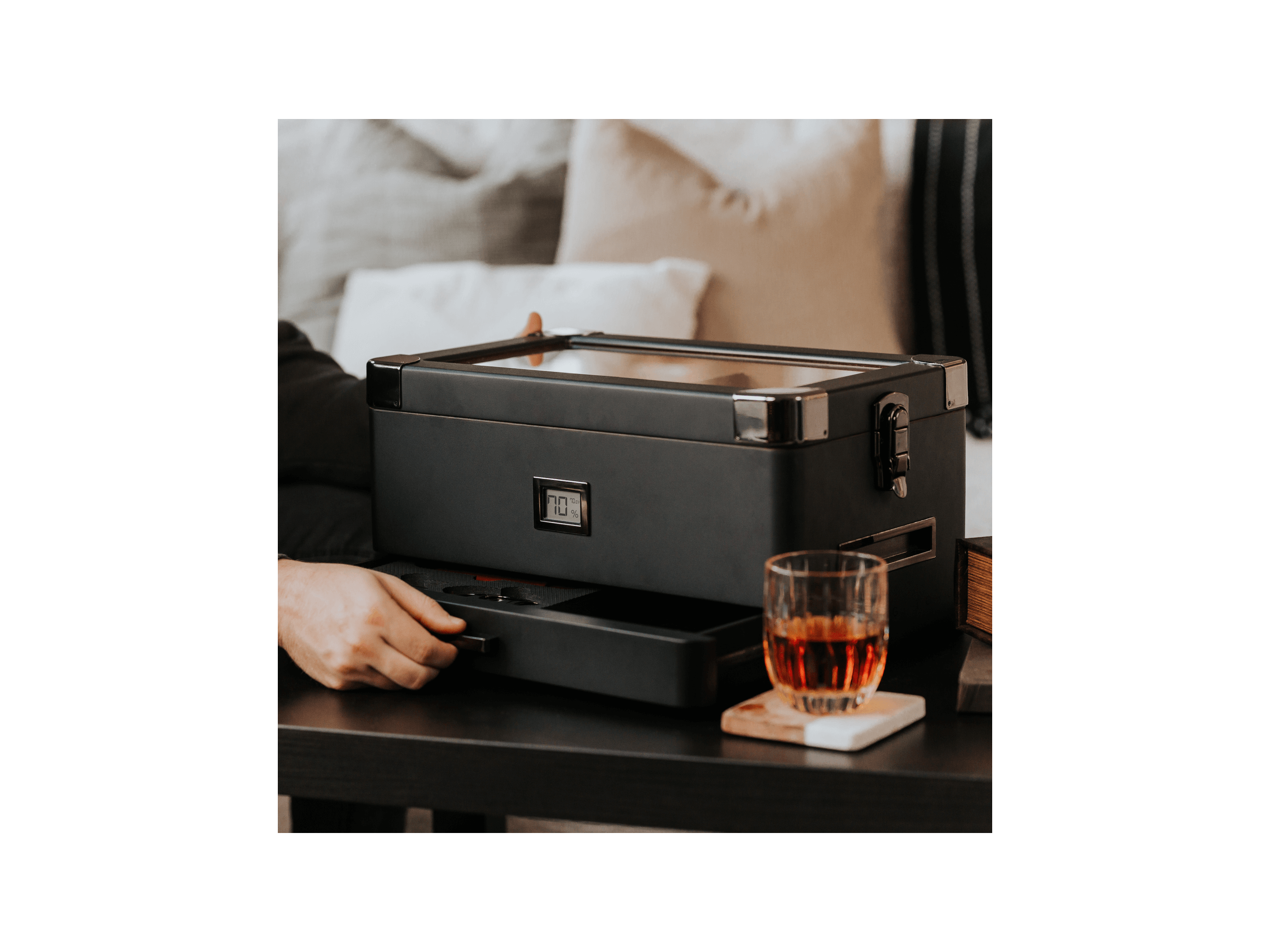 Humidor militaire Black Edition on a table with whiskey glass and modern design, showcasing its unique black matte finish.