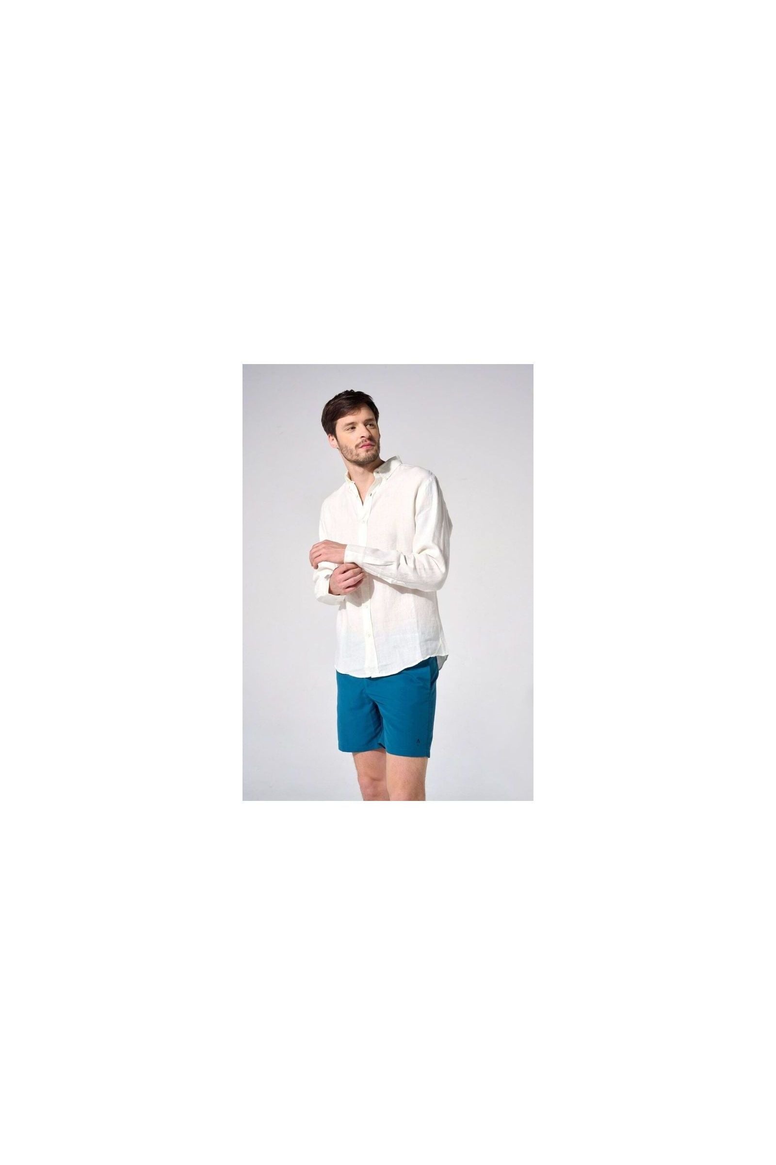 Homme en chemise en lin naturel blanc et short bleu, affichant une coupe classique et élégante.
