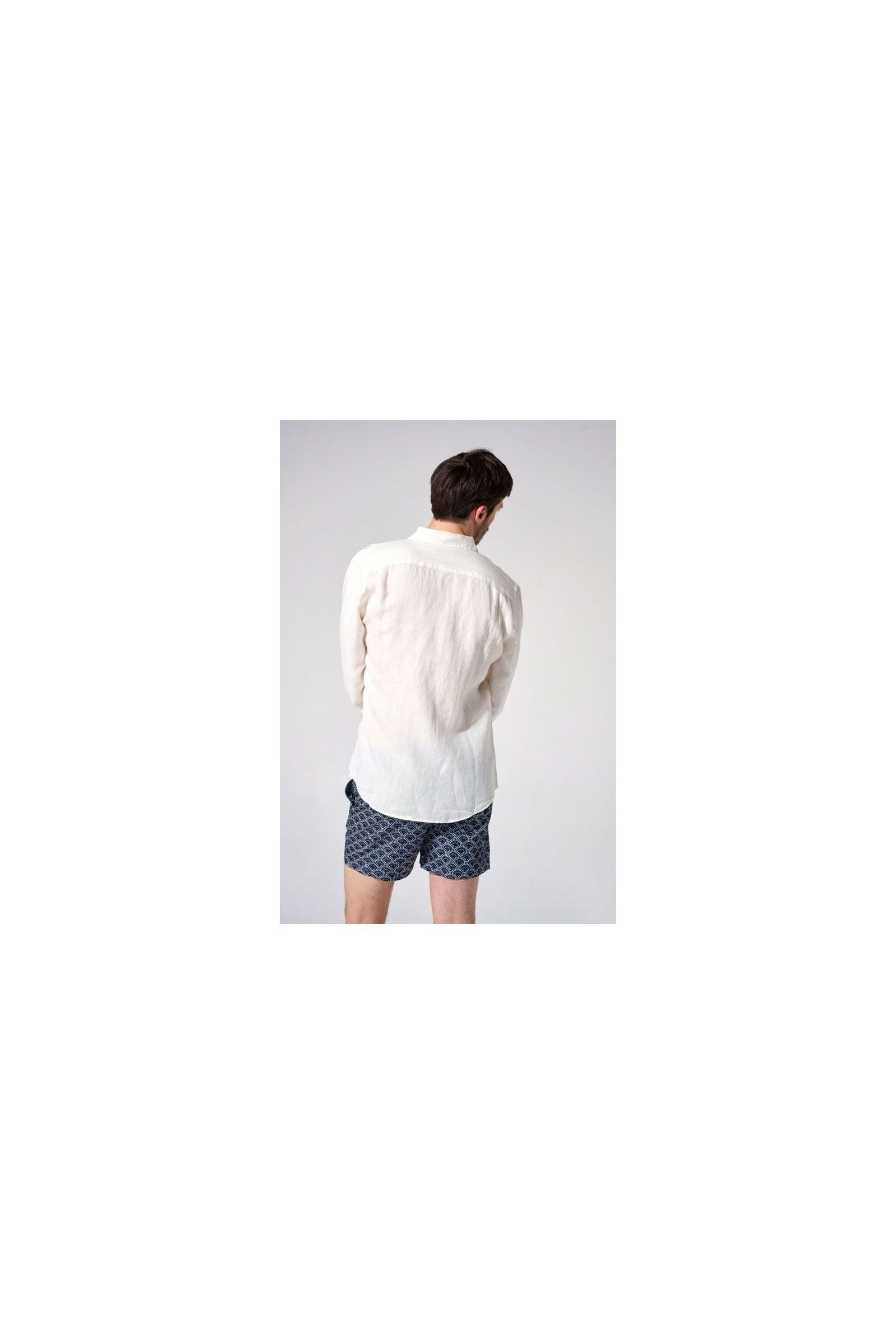 Homme portant une chemise en lin naturel européenne, vue de dos, avec des shorts à motifs, style décontracté.