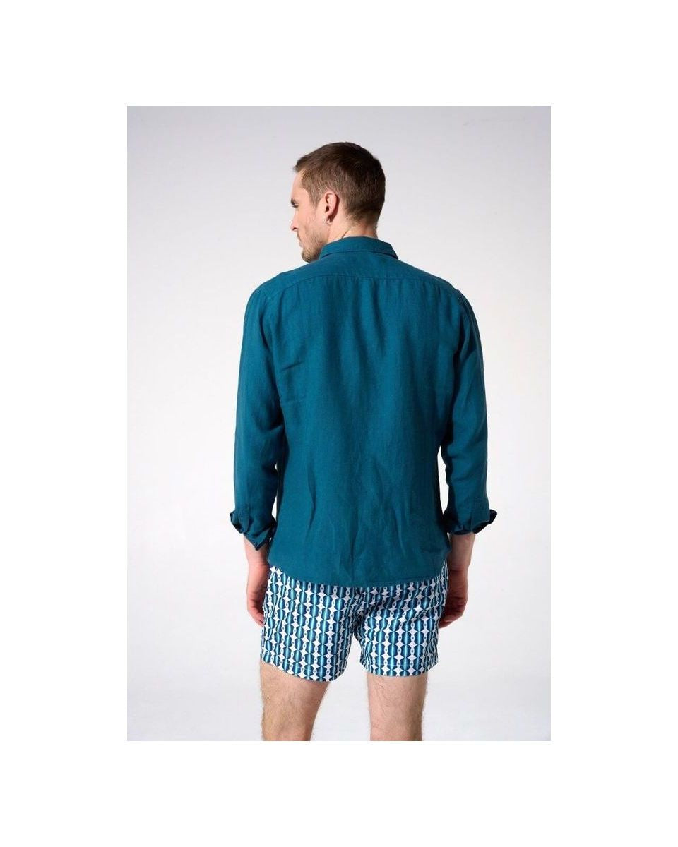 Homme portant une chemise en lin turquoise vue de dos, associée à des shorts imprimés.