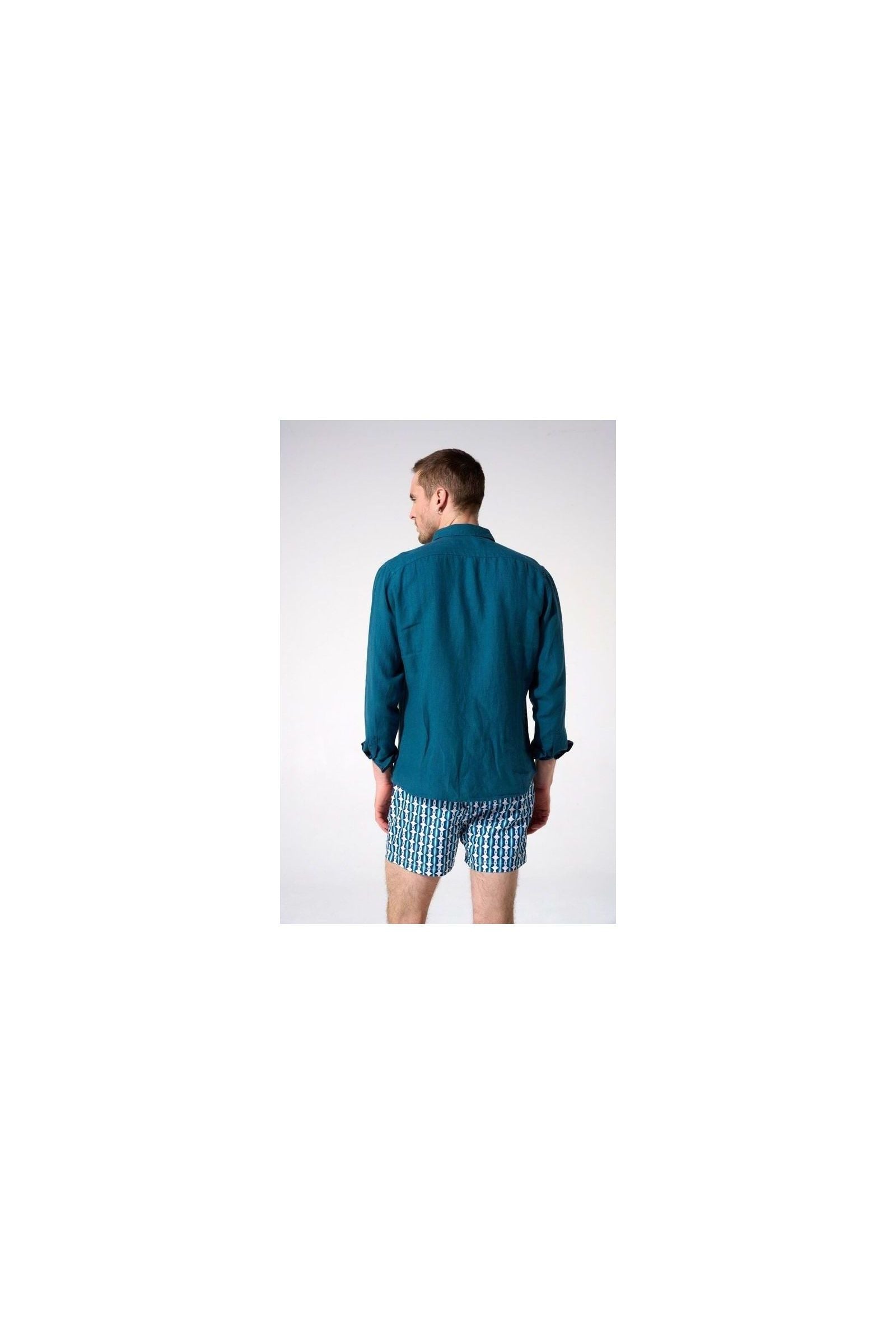 Homme portant une chemise en lin turquoise vue de dos, associée à des shorts imprimés.