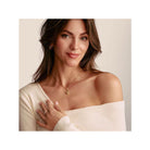 Woman wearing a charm pendant necklace featuring delicate birds and a heart, showcasing elegance and style.