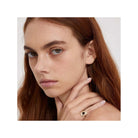 Woman wearing a pinkie ring with intricate design, showcasing elegance and style.